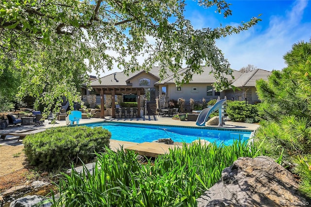 view of swimming pool with a patio area, a pergola, and a water slide