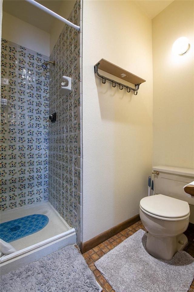 bathroom with tiled shower and toilet