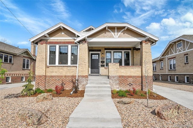 craftsman-style home featuring brick siding and a porch