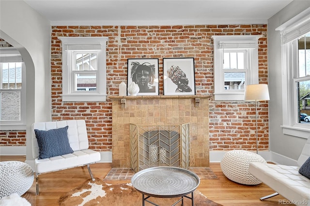 living area with arched walkways, baseboards, wood finished floors, and a fireplace