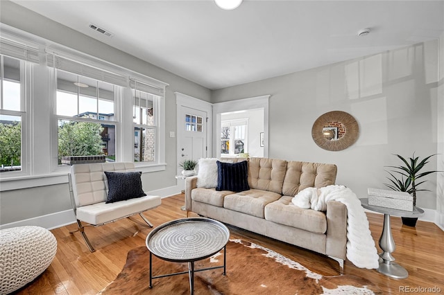 living room featuring baseboards, plenty of natural light, and visible vents