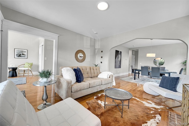 living area featuring baseboards, arched walkways, and wood finished floors