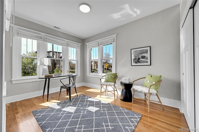 living area with baseboards, visible vents, and wood finished floors