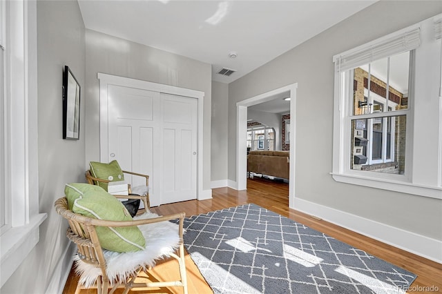 sitting room featuring visible vents, baseboards, and wood finished floors