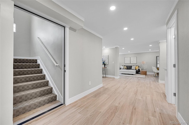 corridor with recessed lighting, ornamental molding, light wood finished floors, and stairs