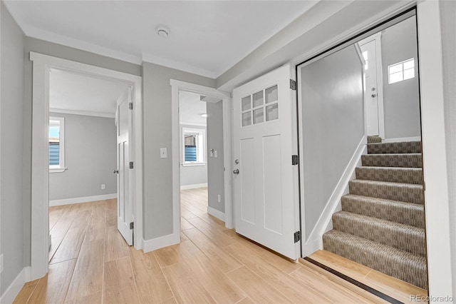 foyer entrance featuring baseboards, light wood-style flooring, and stairway