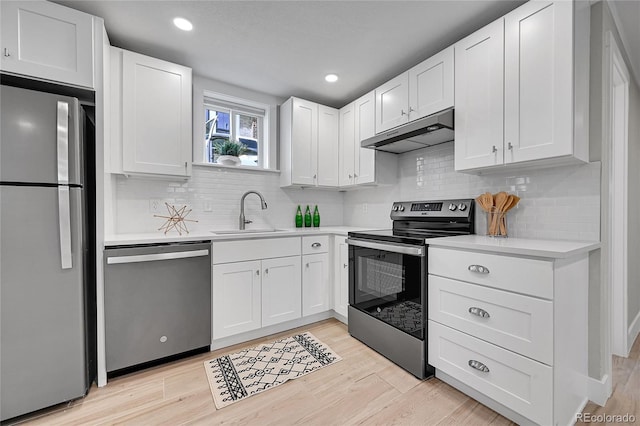 kitchen featuring light countertops, white cabinetry, under cabinet range hood, a sink, and appliances with stainless steel finishes
