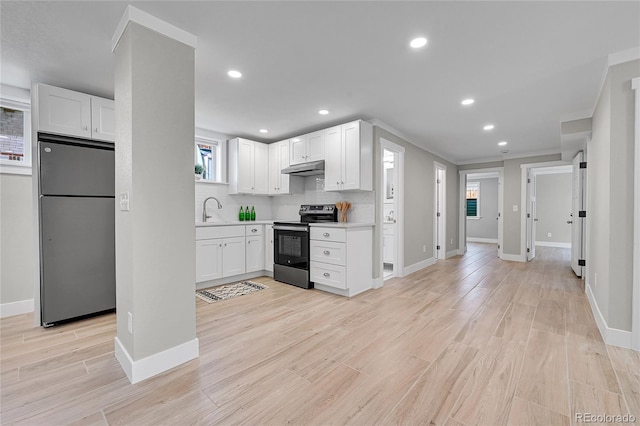 kitchen featuring a sink, baseboards, freestanding refrigerator, electric stove, and white cabinetry