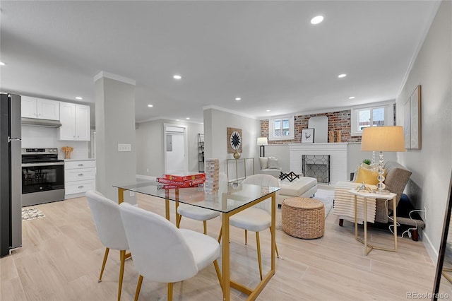 dining space with crown molding, recessed lighting, baseboards, and a brick fireplace
