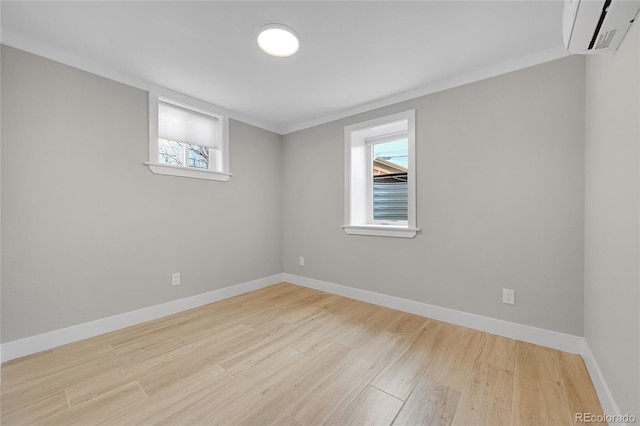 empty room featuring wood finished floors, baseboards, and a wall mounted AC