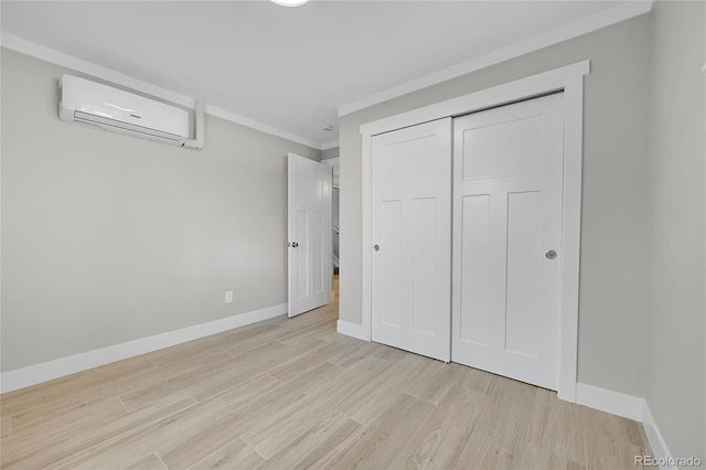 unfurnished bedroom with crown molding, light wood-style floors, an AC wall unit, baseboards, and a closet