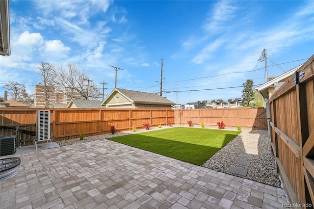 view of yard featuring central AC unit, a fenced backyard, and a patio area