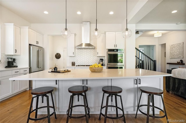 2027 Vallejo Loop, Broomfield, CO 80023 - kitchen featuring wall chimney exhaust hood, backsplash, white cabinets, stainless steel appliances, and recessed lighting