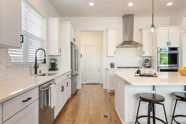 2027 Vallejo Loop, Broomfield, CO 80023 - kitchen with wall chimney exhaust hood, stainless steel appliances, a sink, a breakfast bar area, and backsplash