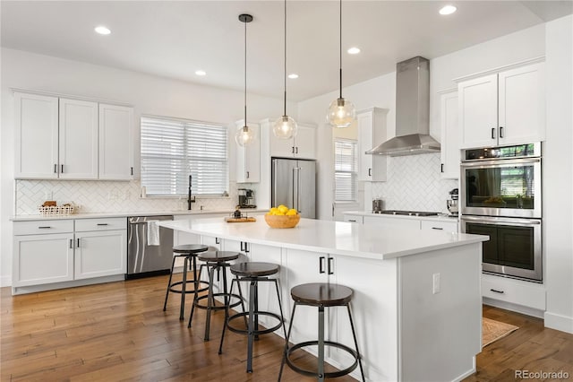 2027 Vallejo Loop, Broomfield, CO 80023 - kitchen with wall chimney range hood, appliances with stainless steel finishes, tasteful backsplash, a center island, and recessed lighting