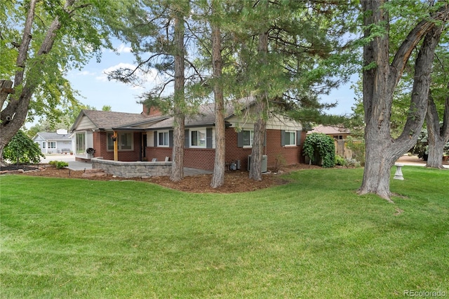 exterior space with brick siding, a yard, and a chimney