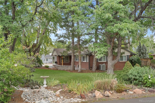 view of front of property with brick siding, a front yard, fence, and central air condition unit