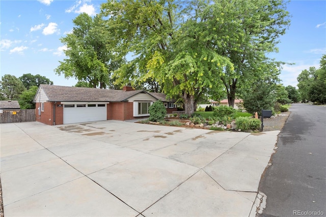 ranch-style house with a garage, brick siding, driveway, and fence