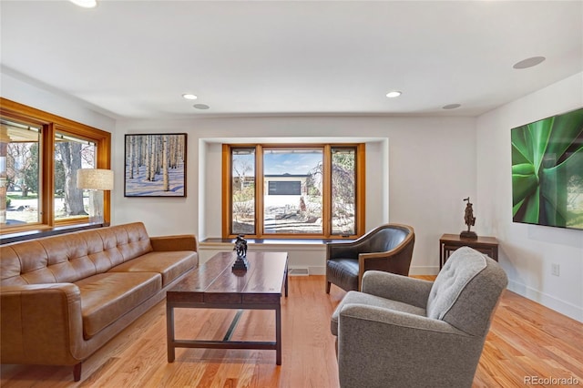 living room featuring visible vents, baseboards, light wood finished floors, and recessed lighting