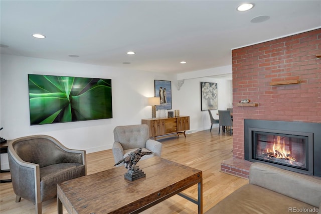 living area with recessed lighting, a brick fireplace, baseboards, and wood finished floors