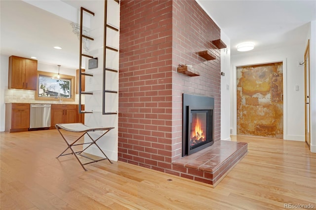unfurnished living room with light wood-style floors, a sink, and a fireplace
