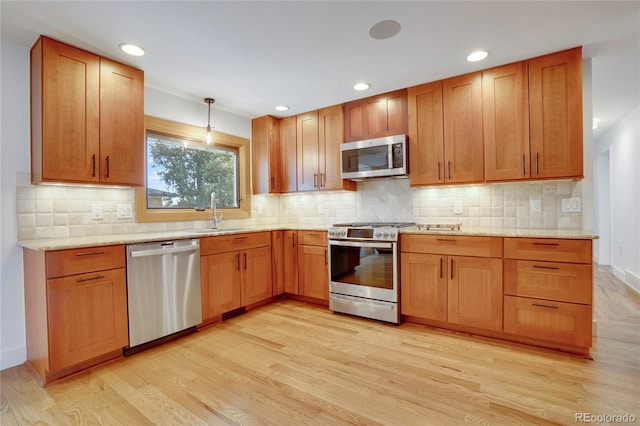 kitchen with stainless steel appliances, tasteful backsplash, light wood-style floors, and a sink