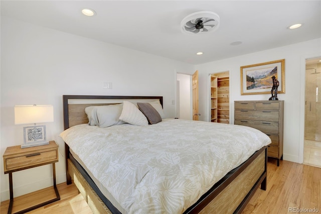 bedroom featuring light wood finished floors, a spacious closet, and recessed lighting