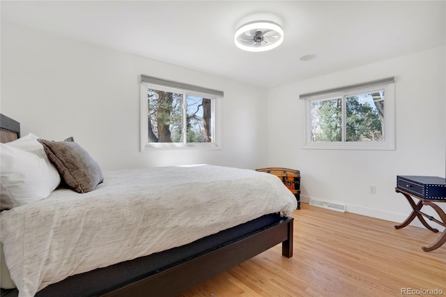 bedroom featuring light wood-style flooring, baseboards, multiple windows, and visible vents