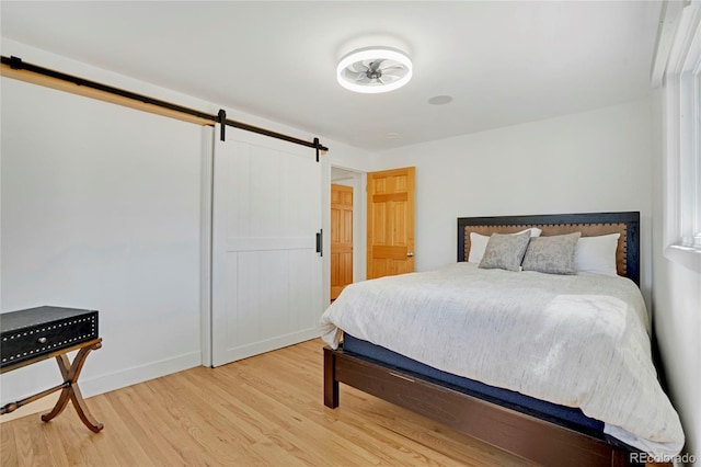 bedroom featuring a barn door, baseboards, and wood finished floors