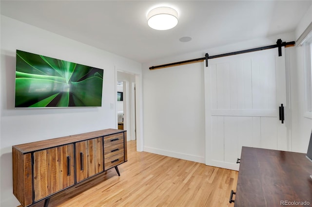 interior space featuring baseboards, a barn door, and wood finished floors