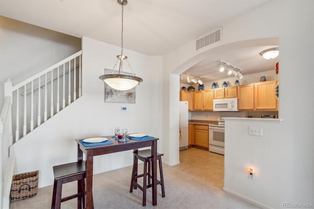 kitchen with white appliances, visible vents, arched walkways, light countertops, and pendant lighting