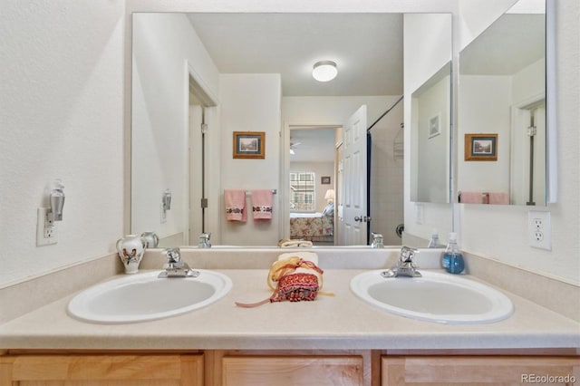 ensuite bathroom featuring double vanity, ensuite bath, and a sink