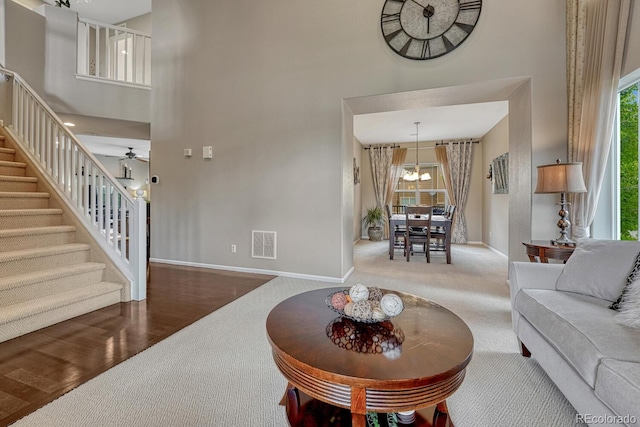 5625 S Buchanan St, Aurora, CO 80016 - carpeted living area featuring a high ceiling, stairs, baseboards, plenty of natural light, and a chandelier