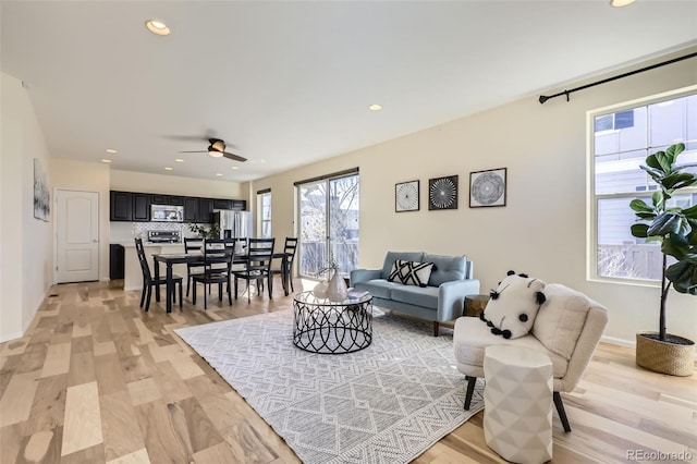 living area with light wood-type flooring, a ceiling fan, and recessed lighting