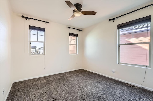 unfurnished room with dark carpet, visible vents, and baseboards