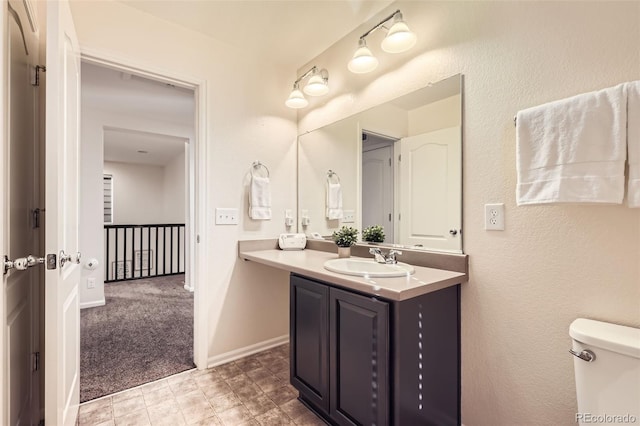 bathroom with toilet, baseboards, and vanity