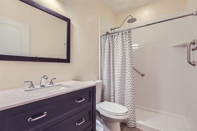 full bathroom featuring toilet, a textured wall, a shower stall, and vanity