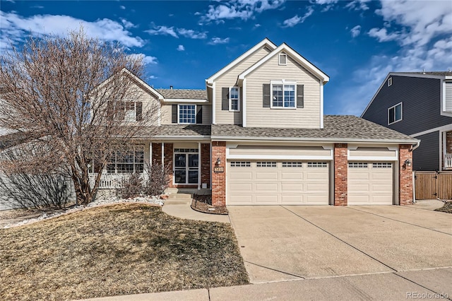 traditional-style house with a shingled roof, a porch, an attached garage, concrete driveway, and brick siding