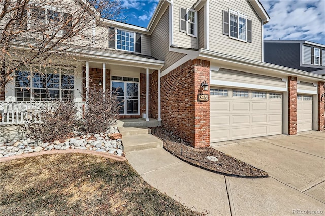 traditional-style house with a garage, covered porch, concrete driveway, and brick siding