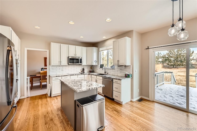 kitchen featuring appliances with stainless steel finishes, a sink, light stone counters, and tasteful backsplash