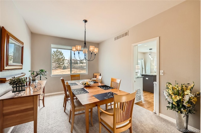 dining area with light carpet, baseboards, visible vents, and a notable chandelier