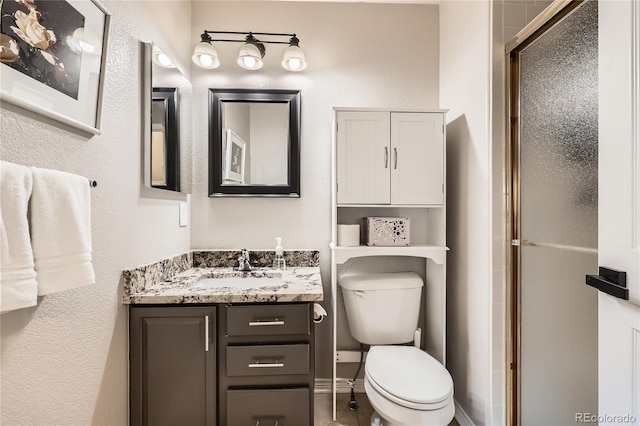 bathroom with a stall shower, baseboards, vanity, and toilet