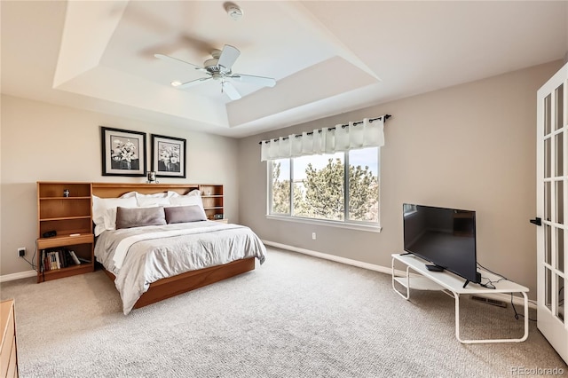 bedroom with carpet flooring, a raised ceiling, and baseboards