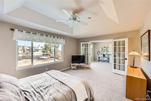 carpeted bedroom with a tray ceiling, french doors, visible vents, ceiling fan, and baseboards