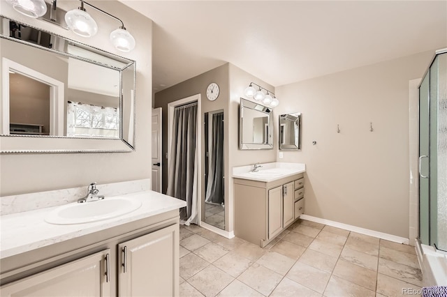 full bathroom featuring baseboards, two vanities, a sink, and a shower stall