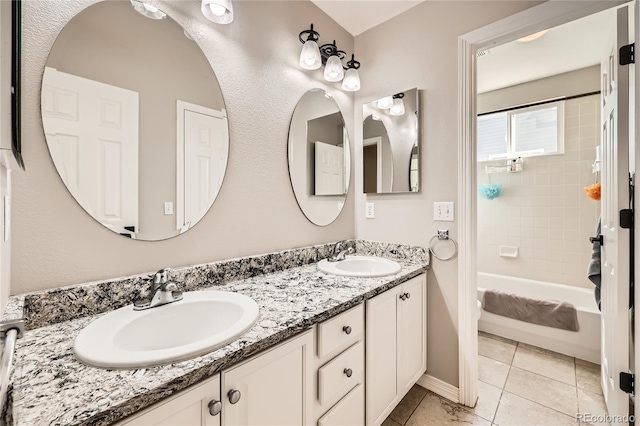 bathroom with double vanity, shower / bathing tub combination, tile patterned flooring, and a sink