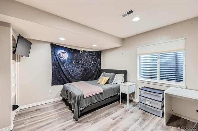 bedroom with wood finished floors, visible vents, and baseboards