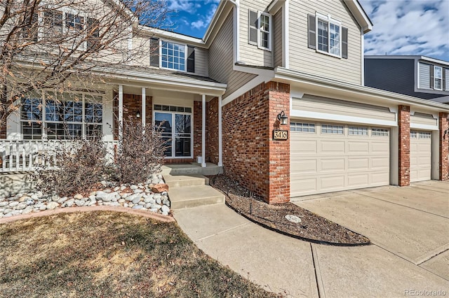 traditional-style home featuring a porch, an attached garage, concrete driveway, and brick siding