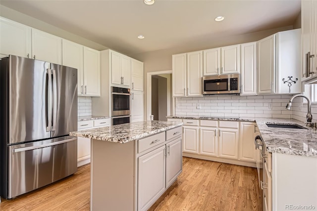 3416 Hawthorne Dr, Highlands Ranch, CO 80126 - kitchen featuring stainless steel appliances, a sink, a kitchen island, white cabinets, and light wood finished floors