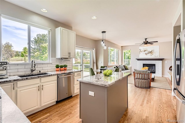 3416 Hawthorne Dr, Highlands Ranch, CO 80126 - kitchen with appliances with stainless steel finishes, a sink, a fireplace, light stone countertops, and light wood finished floors